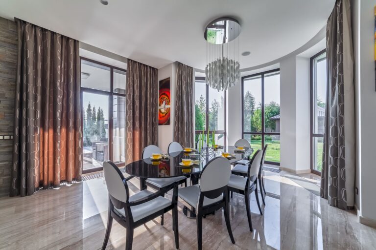 Овальный черный стол в интерьере серо-бежевой столовой