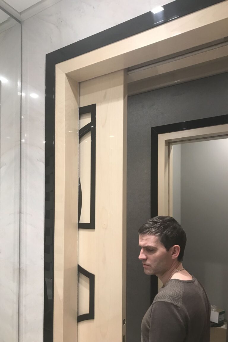 Холл в отделке белым мрамором и зеркалами с контрастным дверным проемом