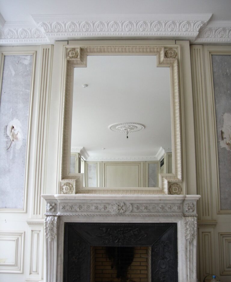Оформление зеркала над камином резной рамой цвета слоновой кости