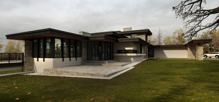 Левый фасад дома из природного камня и светлой отделки с каменной террасой