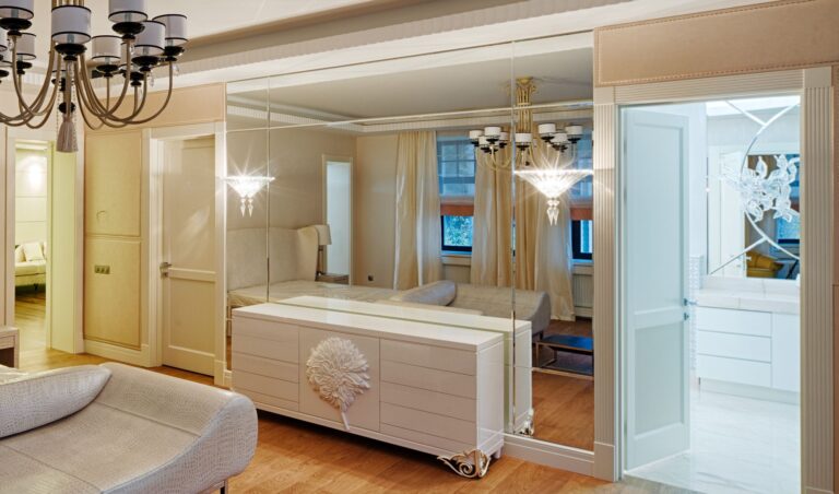 Спальня цвета слоновой кости с зеркальной стеной и белым буфетом