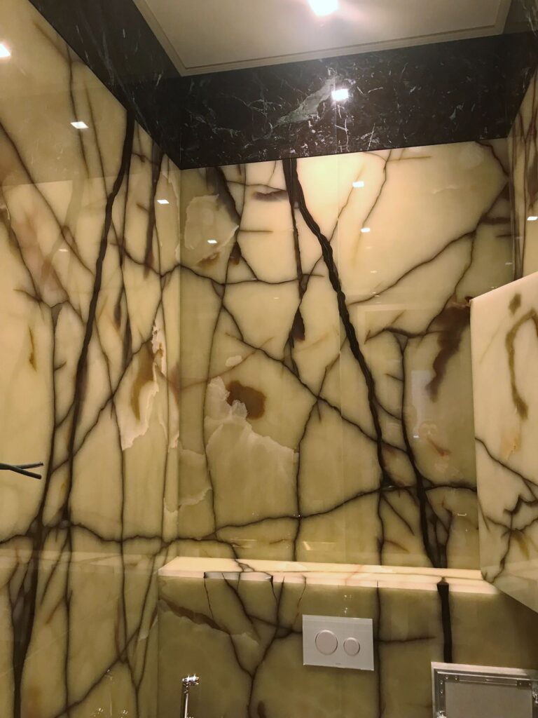 Санузел с мраморными панелями цвета слоновой кости с коричневыми прожилками