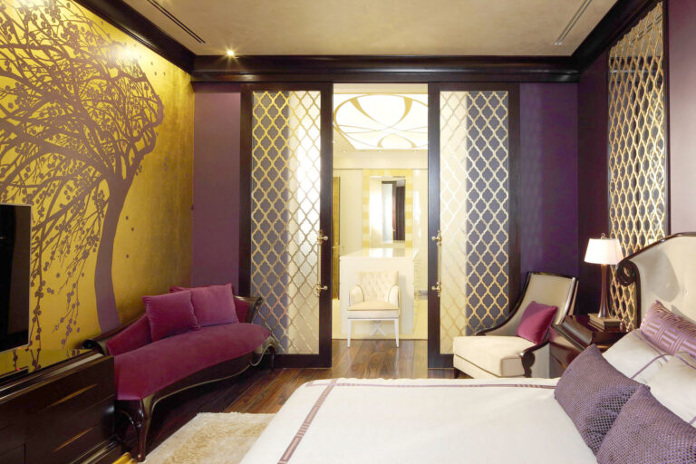 Темная спальня с бордовым бархатным шезлонгом и креслом цвета слоновой кости