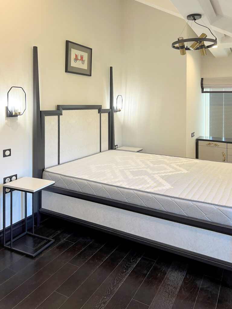 Черная кровать в светлом интерьере спальни