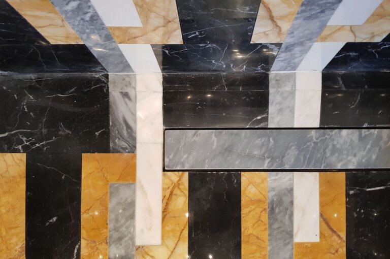 Серая мраморная планка, закрывающая слив в душевой кабине