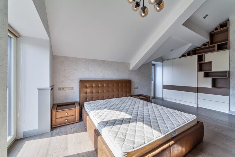 Кожаная мебель и сложный наклонный потолок в дизайне спальни