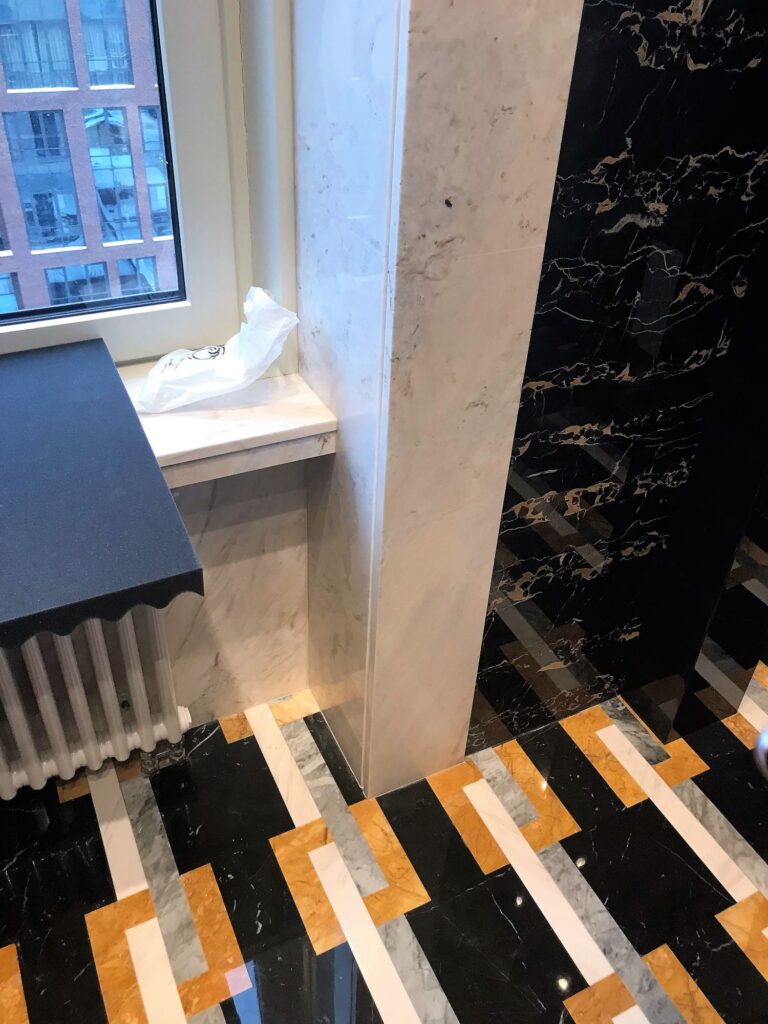 Белый мрамор в отделке оконного проема в интерьере санузла