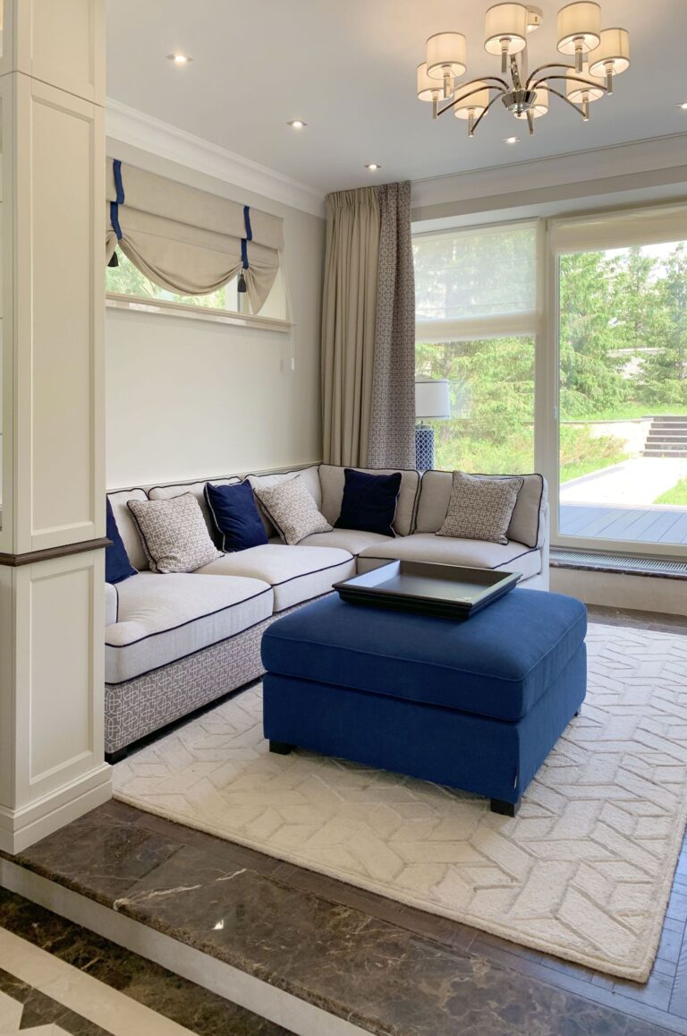 Дизайн белой гостиной с синим пуфом